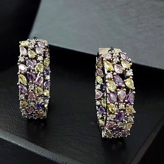 A pair of rectangular hoop earrings with multiple rows of marquise-cut gemstones in purple, yellow, and clear settings, displayed on a black textured surface.